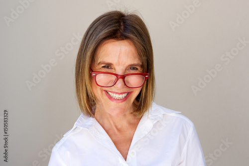 Close up smiling businesswoman with glasses against white wall