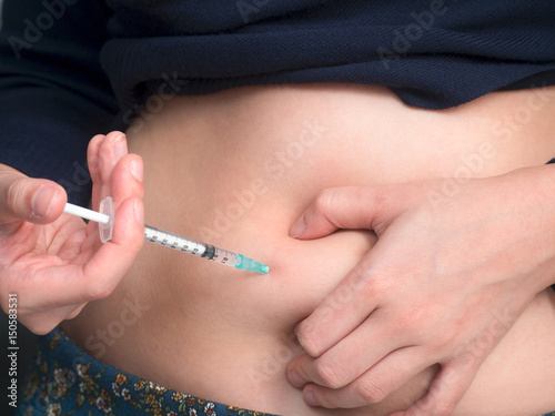 close up of woman with syringe making insulin injection to herself at home