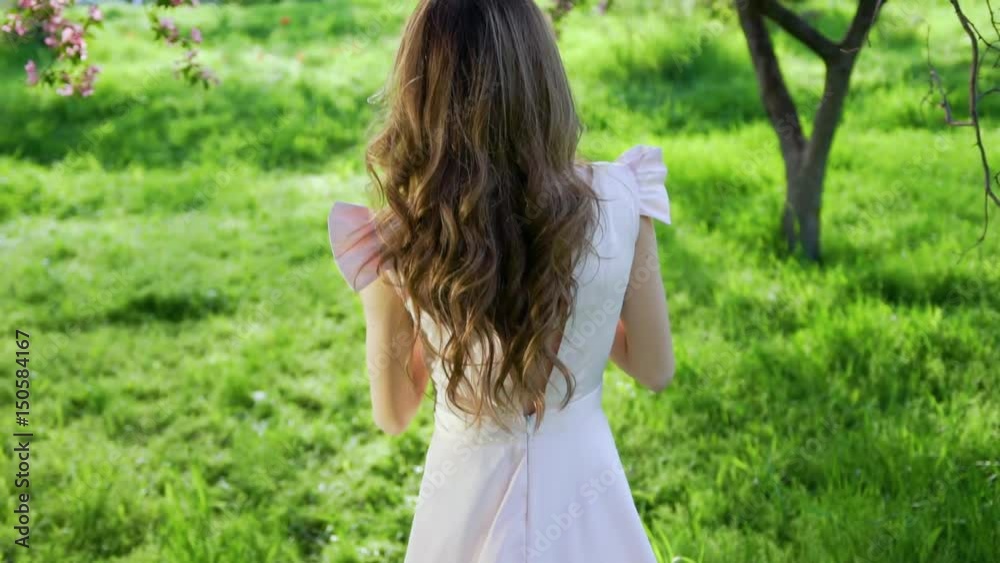 Smiling happy attractive woman goes among flowered garden and turns around Smiling happy attractive woman goes among flowered garden and turns around