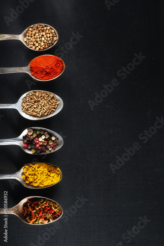 spoons with salt and spices on black chalkboard