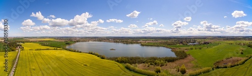 Aerial view panorama of colorful agricultural fields with a lake under blue sky in germany