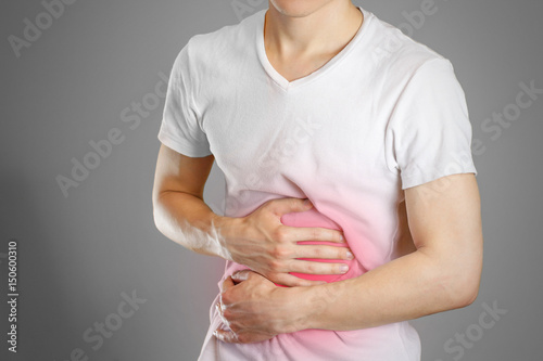 A man holds the stomach. The pain in his chest. Heartburn. Stomach hurts. Sore point highlighted in red. Closeup. Isolated photo
