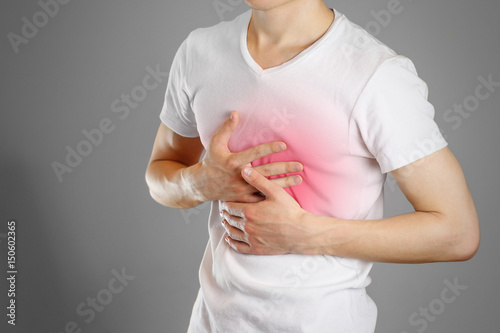 A man holds the Breasts. The pain in his chest. Heartburn. Stomach hurts. Sore point highlighted in red. Closeup. Isolated photo