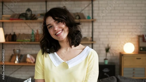 portrait of young cute and enamored woman with dark hair smile flirty and glancing with shy to the camera photo