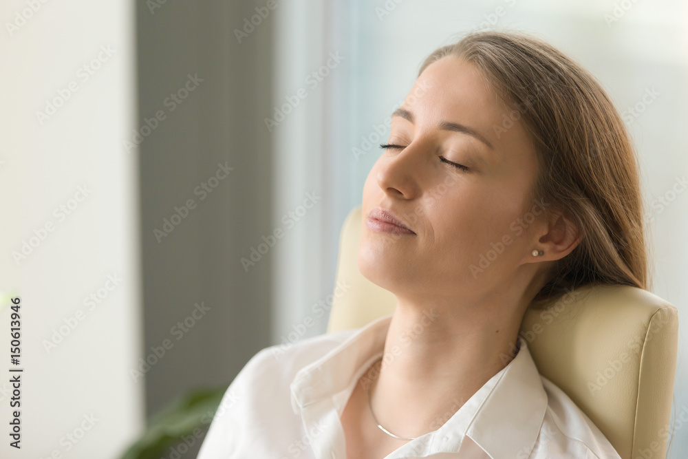 Tired woman lying on back chair with closed eyes. Businesswoman doing deep relaxation exercises during hard working day. Beautiful girl dreaming about future in office. Short meditation at workplace