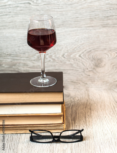 A glass of red wine and books on the table. The concept of rest