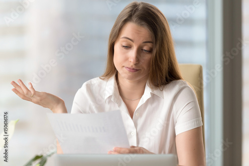 Businesswoman upset because of low financial results. Sad female entrepreneur reading document with bad statistics. Skeptical woman examines confusingbusiness report letter. Forecast falling of profit