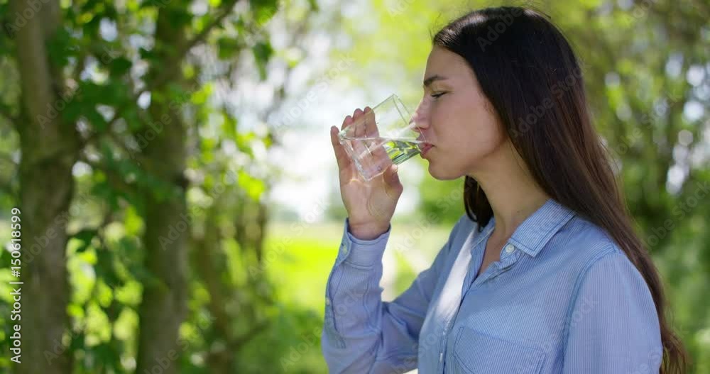 Beautiful young girl holding a glass and drinking naturally clean water, in the background of nature. Concept: ecology, purity, diet, natural pure from sources, environment, refreshing, healthy. Beautiful young girl holding a glass and drinking naturally clean water, in the background of nature. Concept: ecology, purity, diet, natural pure from sources, environment, refreshing, healthy.