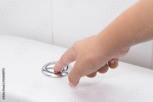 Fotografia Close up of finger pushing a flush toilet button for cleaning