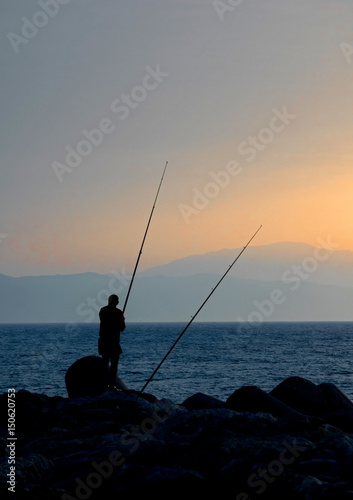 Silueta de un pescador en el mar durante la madrugada. Benalmádena. Málaga. España.