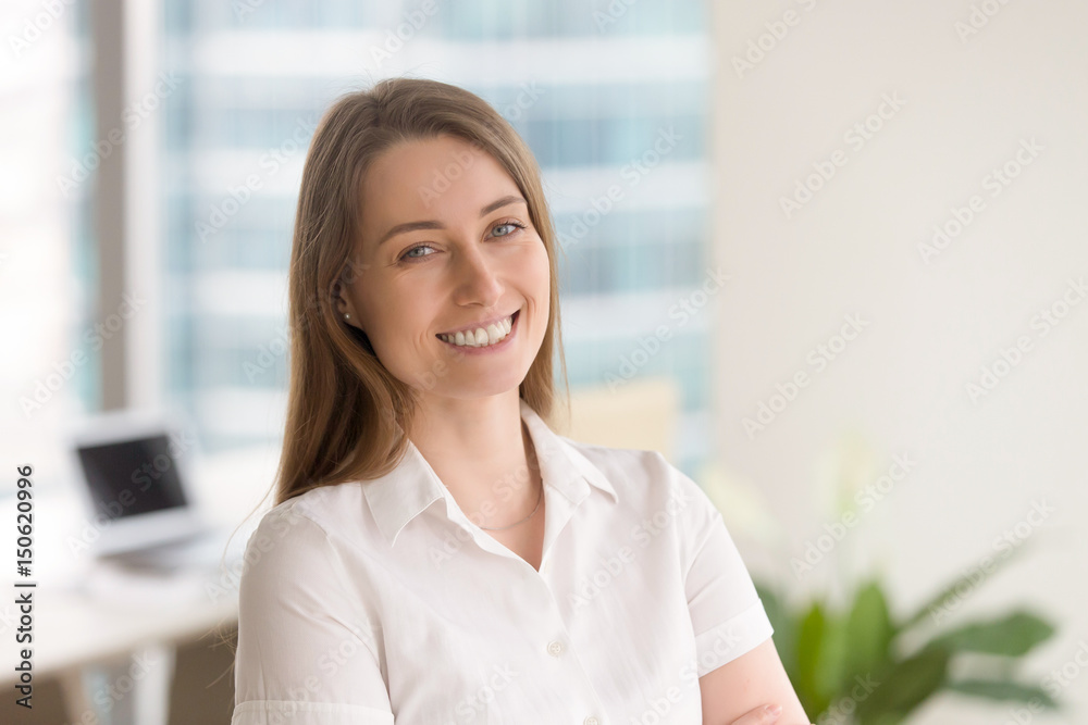 Happy business woman smiling in office interior. Attractive female entrepreneur posing, looking at camera with positive emotions. Smiling businesswoman enjoys great success at work. Head shot portrait Happy business woman smiling in office interior. Attractive female entrepreneur posing, looking at camera with positive emotions. Smiling businesswoman enjoys great success at work. Head shot portrait