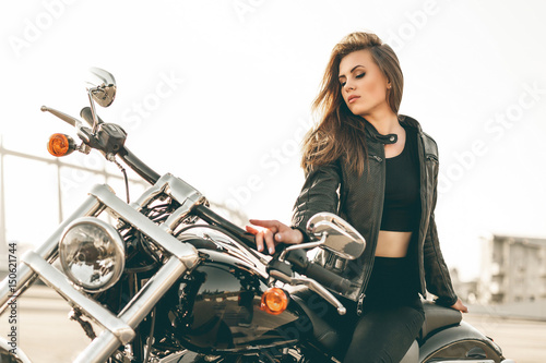 Girl on a motorcycle. She is beautiful, posing on a motorcycle at sunset © belyjmishka