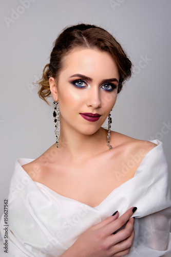Pretty young woman s studio portrait on gray background  dark makeup