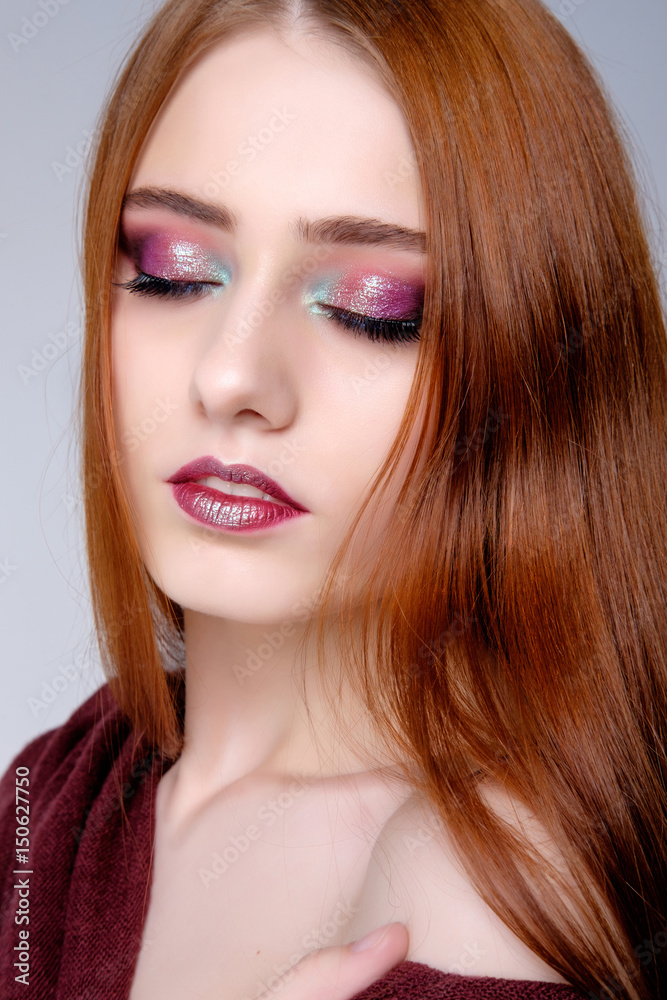 Pretty young redghead woman's studio portrait on gray background, pink makeup Pretty young redghead woman's studio portrait on gray background, pink makeup