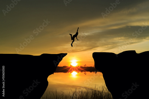 Man jumping over cliff on sunset background,Business concept idea