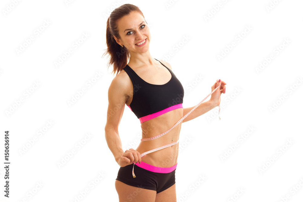 smiling sports girl in top and shorts takes the waist measuring tape smiling sports girl in top and shorts takes the waist measuring tape