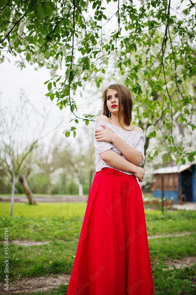 Portrait of beautiful girl with red lips at spring blossom garden, wear on red dress and white blouse. Portrait of beautiful girl with red lips at spring blossom garden, wear on red dress and white blouse.