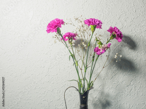 Fototapeta Naklejka Na Ścianę i Meble -  Bouquet of carnations with shadow on the grungy wall
