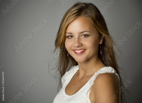 Happy smiling young woman face on gray background