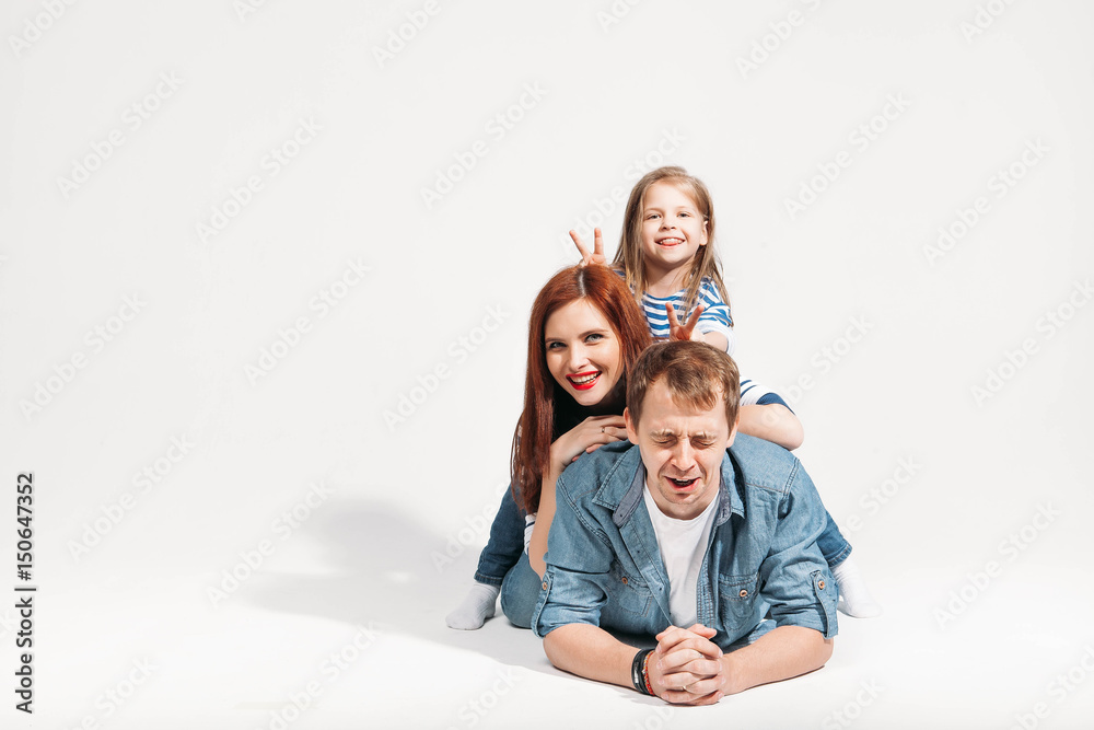 stressed lying young dad with daughter and wife on his back