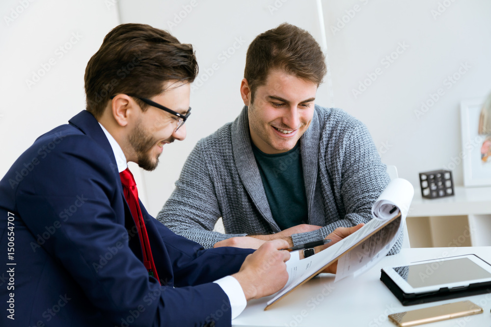 Business young man explaining terms of contract to his client in the office. Business young man explaining terms of contract to his client in the office.