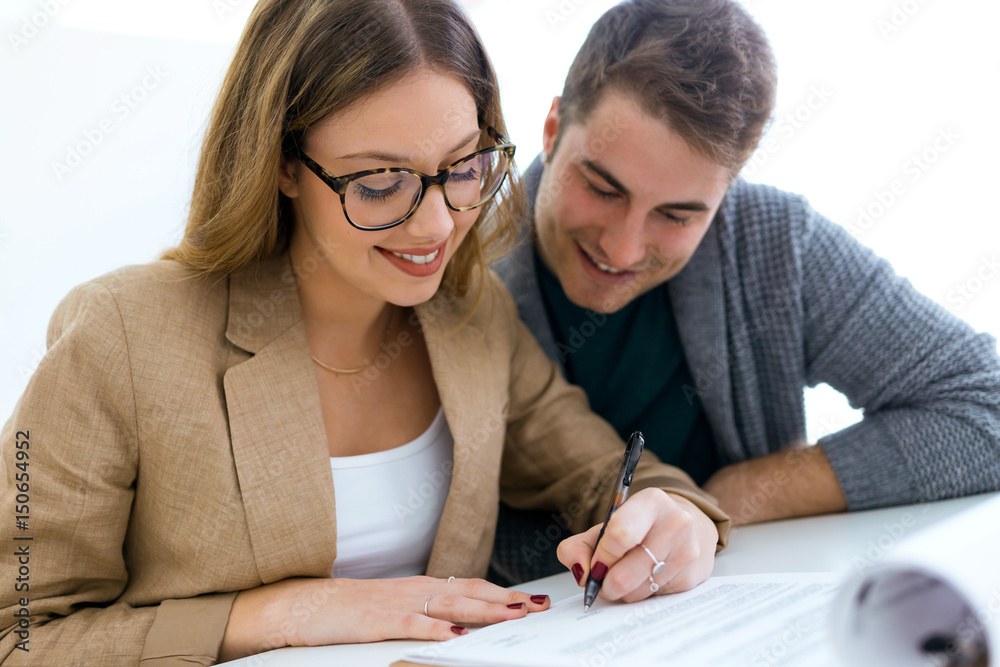Beautiful young couple signing financial contract in the office. Beautiful young couple signing financial contract in the office.