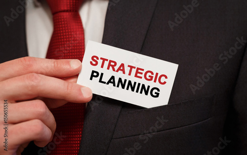 Businessman putting a card with text Strategic Planning in the pocket