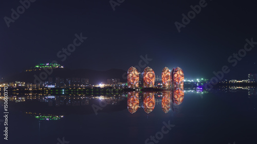 Night view of an artificial Phoenix island and Sanya city illuminated with city lights.