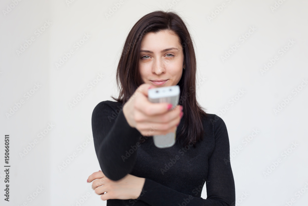 Girl changes TV program, pressing the button on the remote control Girl changes TV program, pressing the button on the remote control