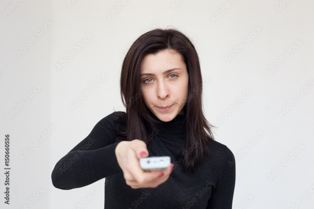 The dissatisfied girl switches the program on TV. She is angry with the information she saw The dissatisfied girl switches the program on TV. She is angry with the information she saw
