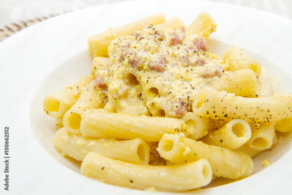 white dish with penne and carbonara sauce