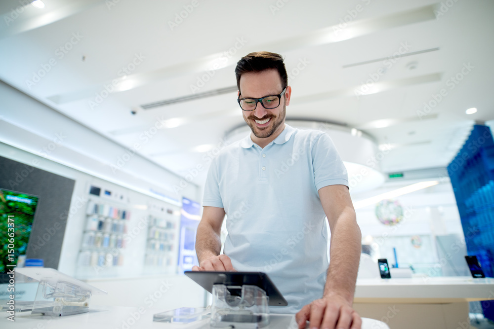 Happy young man choosing his new tablet. Shopping in tech store. Happy young man choosing his new tablet. Shopping in tech store.