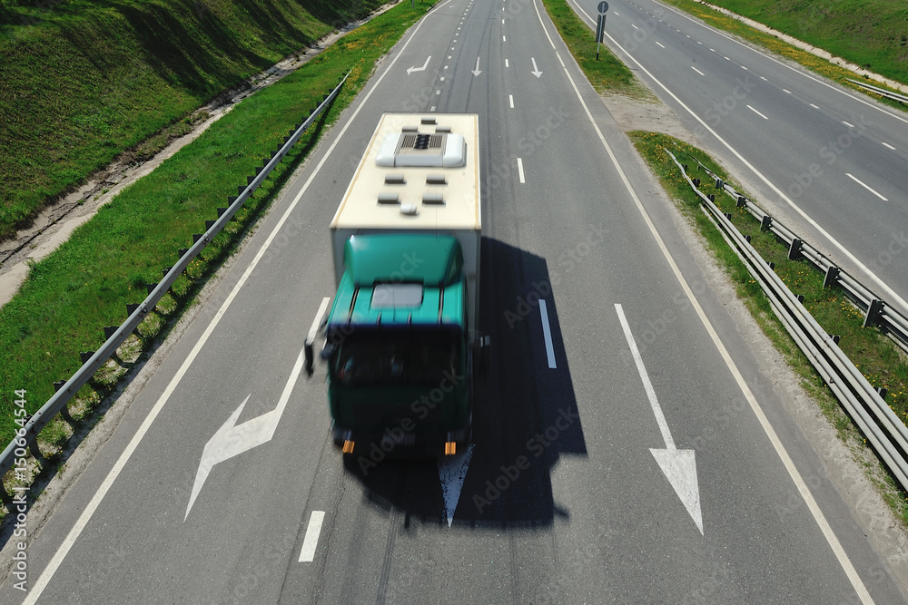 The truck is driving along the highway in a sunny day The truck is driving along the highway in a sunny day