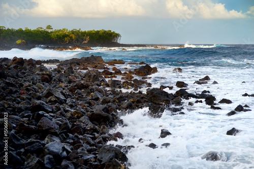 Beautiful pink tinted waves breaking on a rocky beach at sunrise on east coast of Big Island of Hawaii