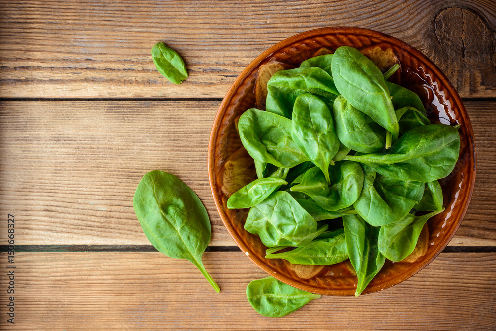 Fresh spinach leaves in bowl on rustic wooden table. Fresh spinach leaves in bowl on rustic wooden table.