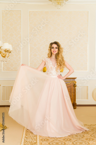 Portrait of beautiful young bride. A girl is posing in a hotel room. The lady is spinning in her wedding dress