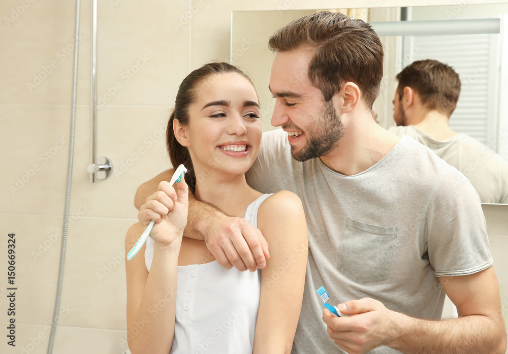 Fototapeta premium Young happy couple brushing teeth in bathroom