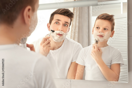 Father and son shaving in b...