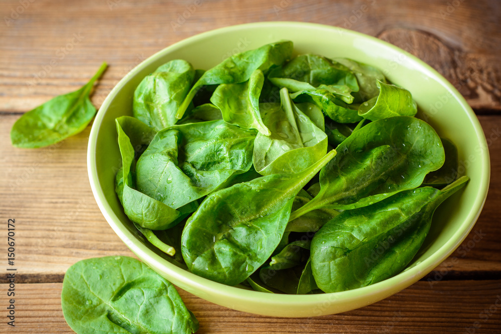 Washed fresh spinach leaves in bowl on rustic wooden table. Washed fresh spinach leaves in bowl on rustic wooden table.