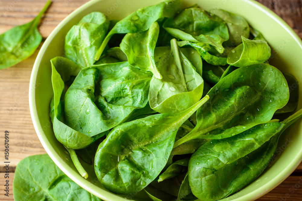Washed fresh spinach leaves in bowl on rustic wooden table. Washed fresh spinach leaves in bowl on rustic wooden table.