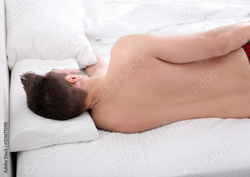 Young man lying on bed with...