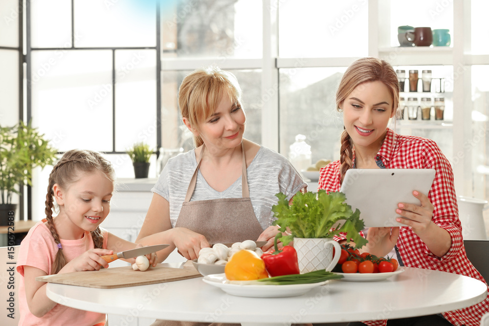 Young woman with mother and daughter cooking in kitchen Young woman with mother and daughter cooking in kitchen
