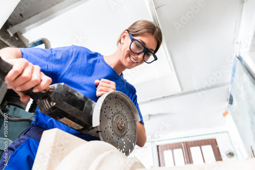 Female sculptor cutting stone with angle grinder photo