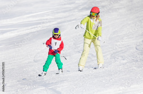 Little boy training skiing with female instructor
