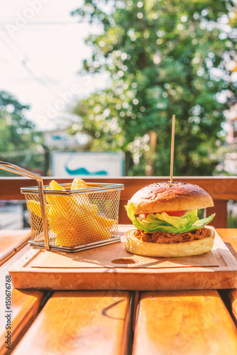 Meat burger with fries on a wooden board in the pub, top view, copy space, outdoor background.
