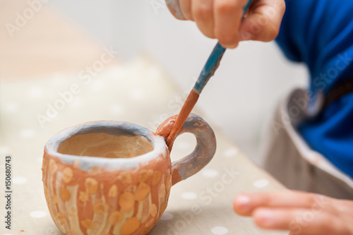 The boy is painting the cup. A cup closeup