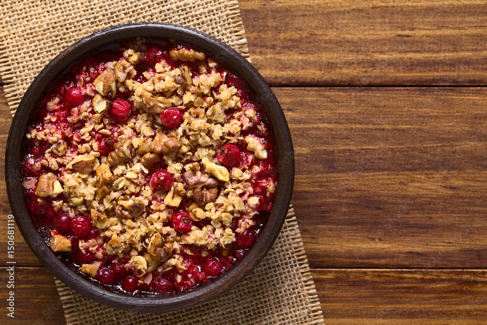 Redcurrant crumble or crisp with oatmeal and walnut on top baked in rustic bowl, photographed overhead on dark wood with natural light (Selective Focus, Focus on the top of the crumble) Redcurrant crumble or crisp with oatmeal and walnut on top baked in rustic bowl, photographed overhead on dark wood with natural light (Selective Focus, Focus on the top of the crumble)