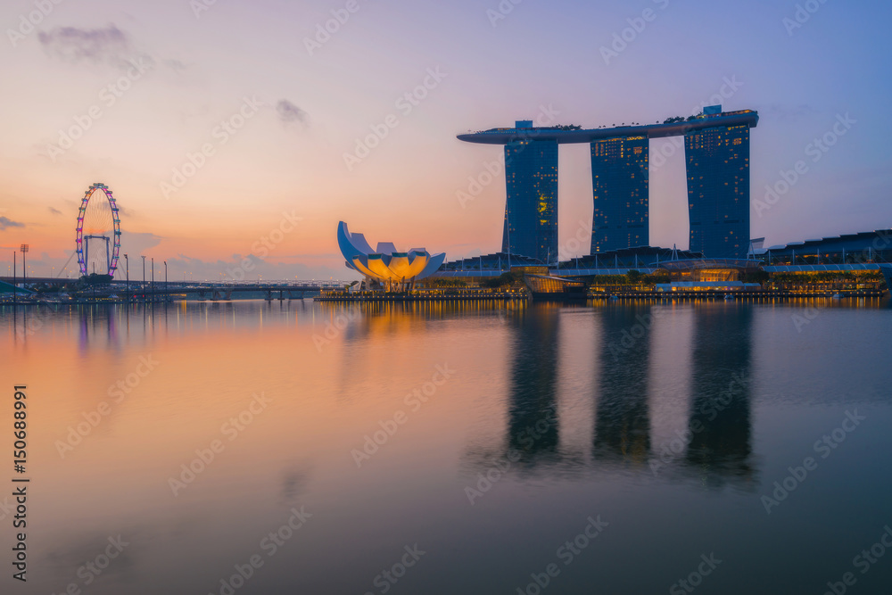 Modern buildings of Singapore skyline landscape in business district with sunrise and reflection in water of Marina Bay