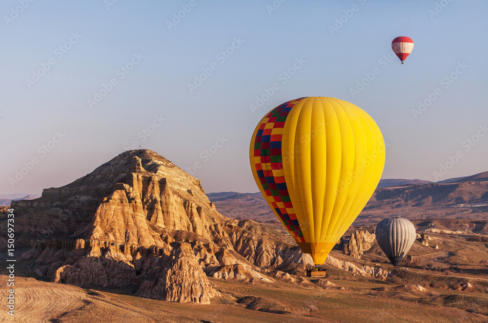 Naklejka premium hot air balloon rises very high in blue sky above white clouds, bright sun shines