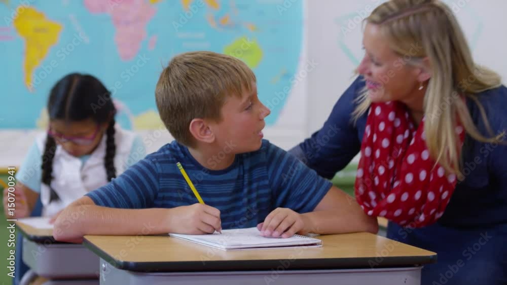 Teacher helping student with writing project in school classroom Teacher helping student with writing project in school classroom